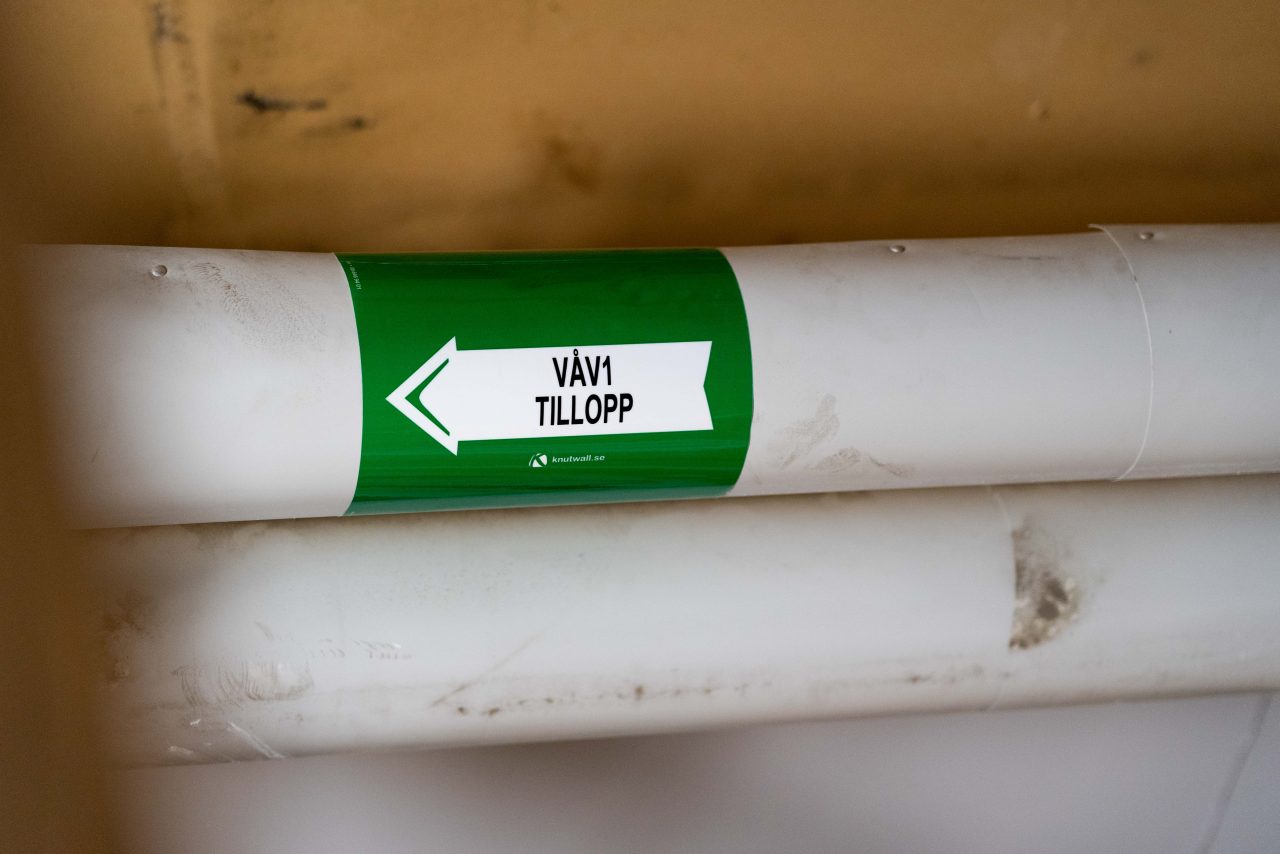 Grön rörmärkning på rör med texten tillopp