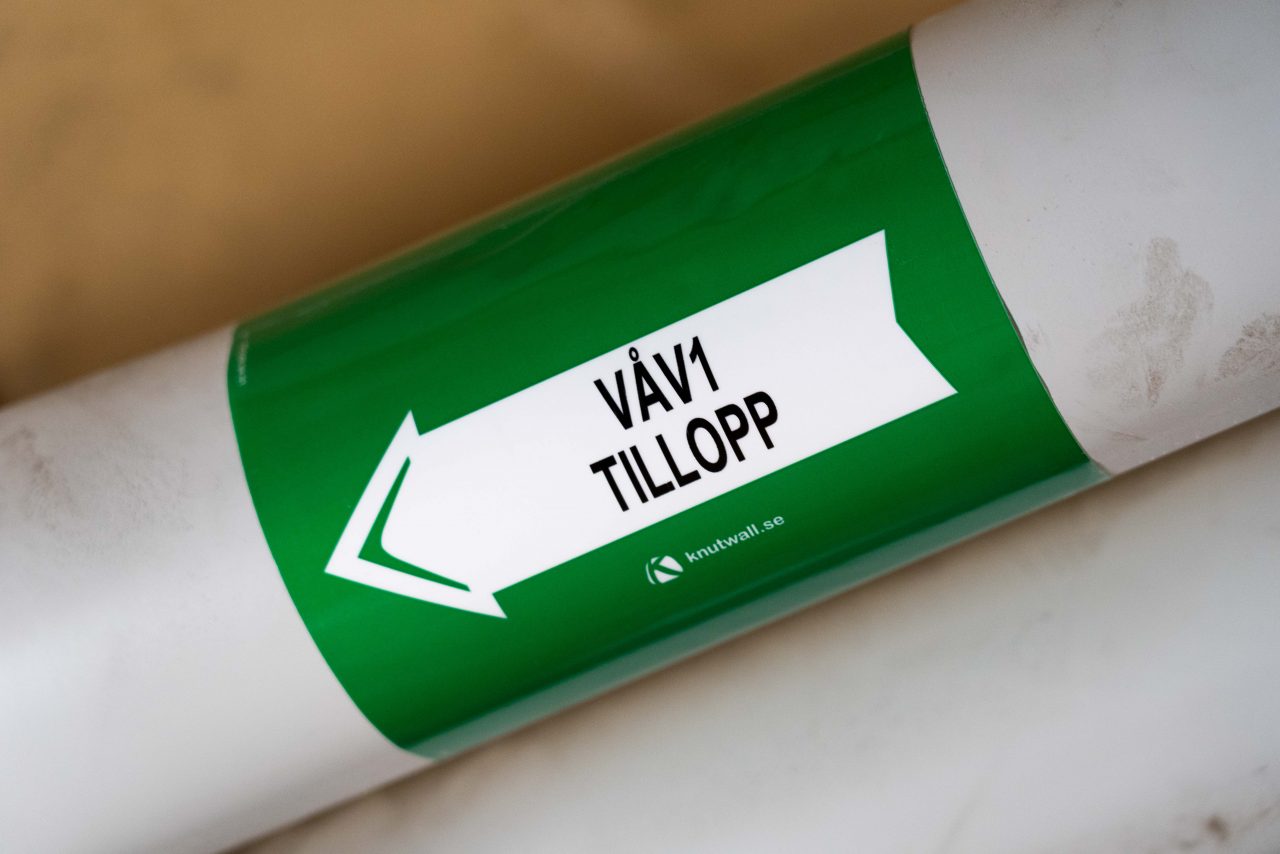Grön rörmärkning med texten tillopp 